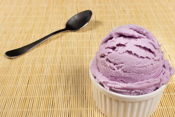 ホワイトポットで提供されるグレープ風味の紫色のアイスクリーム バックグラウンドのスプーンとテキストの空の左下のスペースとのクローズアップ写真 — ストック写真
