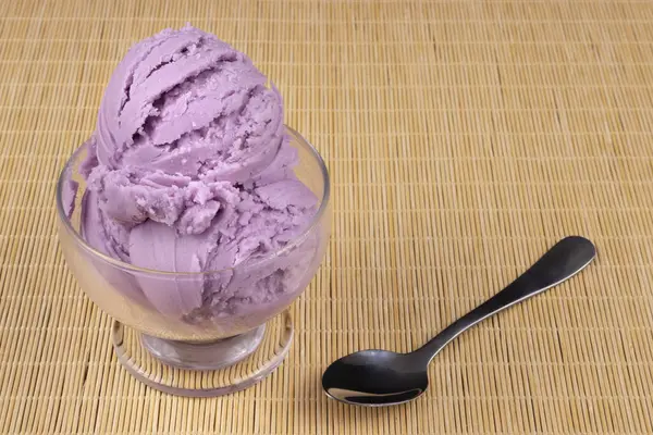 グレープ風味の紫色のアイスクリームは 右側にスプーンが付いた透明なボウルで提供されました フォトグルメアイスクリームパーラー — ストック写真