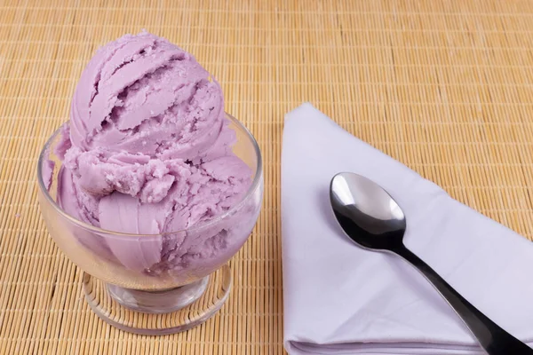 グレープ風味の紫色のアイスクリームは 白いナプキンの側面にスプーン付きのガラスボウルで提供されました 冷凍食品とデザートのクローズアップ写真 アイスクリームパーラー — ストック写真