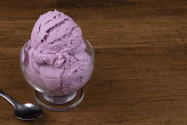 Grape-flavored purple ice cream served in a glass bowl. Gastronomic photography of ice cream. Empty space for texts on the right.