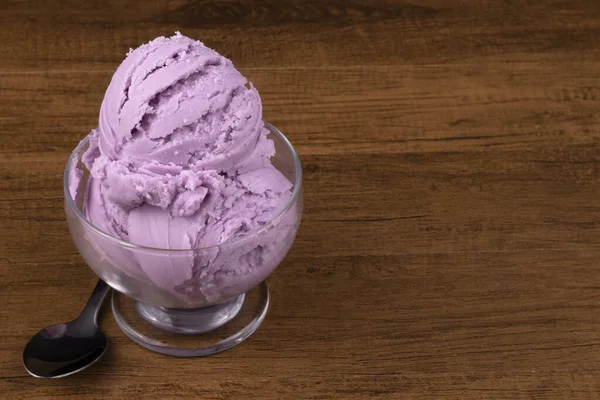 Grape-flavored purple ice cream served in a bowl with a spoon on the side. Free space for text on the right.