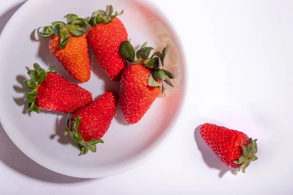 红色的草莓放在一个白色的碗里 一个草莓从碗里出来 文本右上方的空格 — 图库照片