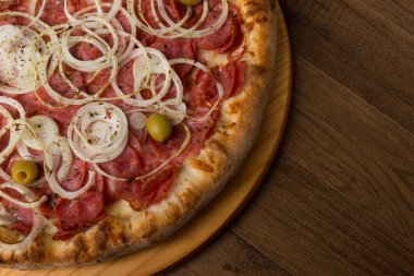 Pepperoni pizza, soğan dilimleri, mozzarella peyniri ve yeşil zeytin. Üst yakın plan fotoğraf. Metinler için doğru boşluk.