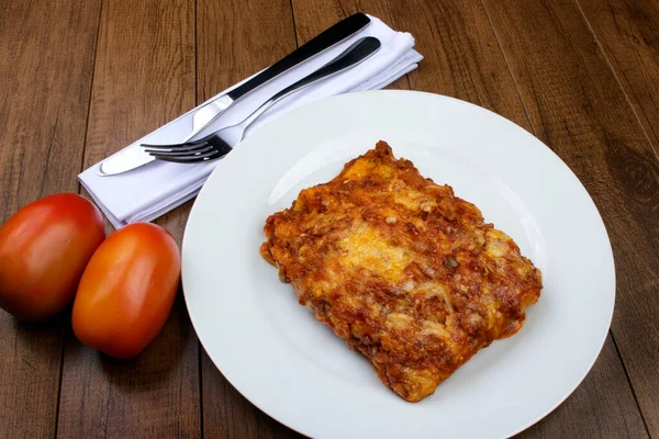 ハムチーズ トマトソース グラウンドビーフで作られたボローニャソースのラザニア ホワイトプレートで食べる ナプキンのカトラリー — ストック写真