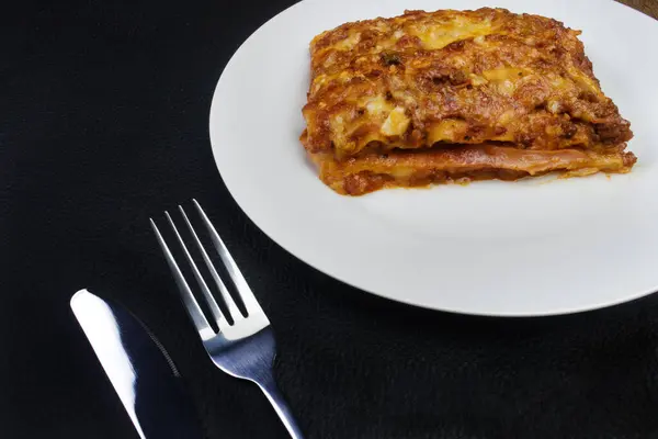 ハムチーズ トマトソース グラウンドビーフで作られたボローニャソースの美味しいラザニア 金属ナイフとフォーク 伝統的なパスタ料理 — ストック写真