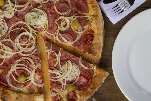 Pepperoni pizza, slices of onions, mozzarella cheese and green olives. Slice of pizza being served. Top gastronomic photography.
