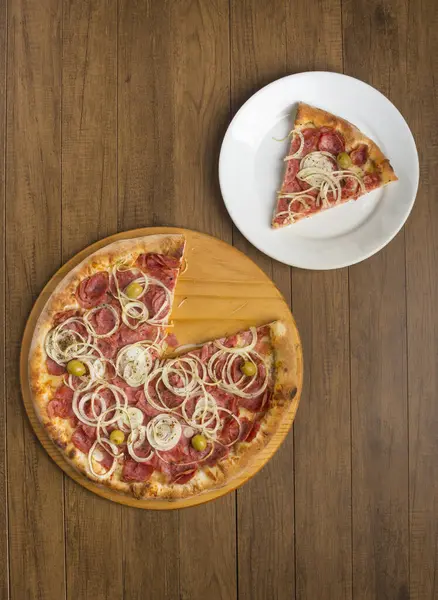 Pepperoni pizza, slices of onions, mozzarella cheese and green olives. Slice of pizza served on the plate. Fast food. Top shot. Diagonally aligned elements with space for texts.