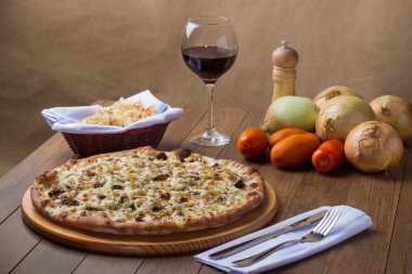 Tahtada etli pizza. Mozzarella, picanha eti, soğan, peynir, domates sosu. Biftek, et, biber öğütücü, bir bardak kırmızı şarap, crostini, çatal ve bıçak..