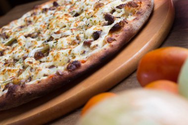 Tahta üzerinde lezzetli et pizzası. Mozzarella, picanha eti, soğan, peynir, domates sosu. Biftek, et. Odaklanmamış domatesli yatay fotoğraf.