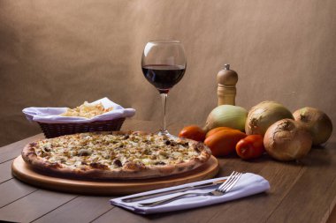 Tahtada etli pizza. Mozzarella, picanha eti, soğan, peynir, domates sosu. Biftek, et, biber öğütücü, bir bardak kırmızı şarap, crostini, çatal ve bıçak. Yatay Fotoğrafçılık.