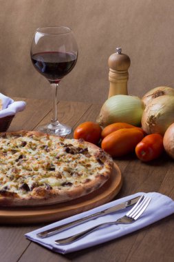 Tahtada etli pizza. Mozzarella, picanha eti, soğan, peynir, domates sosu. Biftek, et, biber öğütücü, bir bardak kırmızı şarap, crostini, çatal ve bıçak. Dikey Fotoğraf.