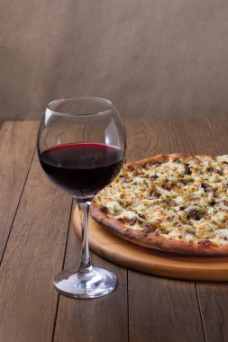 Tahta üzerinde lezzetli et pizzası. Mozzarella, picanha eti, soğan, peynir, domates sosu. Biftek, et. Bir bardak şarap. Restoran fotoğrafı..