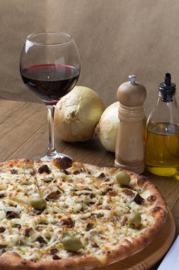 Tahtada etli pizza. Mozzarella, picanha eti, soğan, peynir, domates sosu ve zeytinle yapıldı. Biftek, et, biber öğütücü, bir bardak kırmızı şarap, çatal ve bıçak. Gurme dikey fotoğraf.