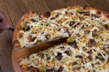 Tahtada etli pizza. Mozzarella, picanha eti, soğan, peynir, domates sosu ve zeytinle yapıldı. Biftek, et. Lezzetli dilimler..