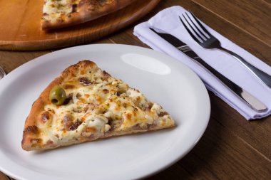 Tabakta servis edilen lezzetli bir dilim. Tahtada etli pizza. Mozzarella, picanha eti, soğan, peynir, sos ve zeytinle yapıldı. Biftek. Çatal ve Bıçak üstte. Açlık.