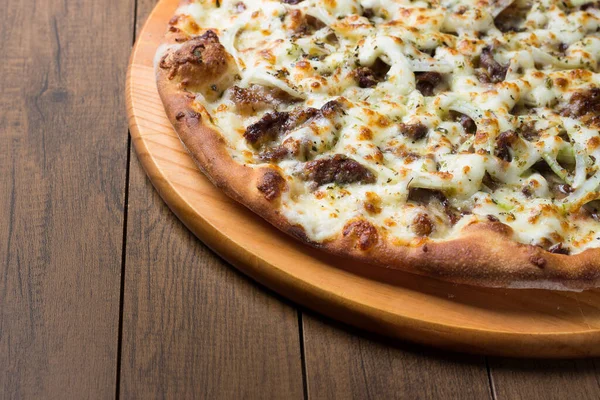 Delicious meat pizza on wooden board. Made with Mozzarella, picanha meat, onion, cheese, tomato sauce. Filet Steak, meat. Horizontal photograph, upper right alignment.