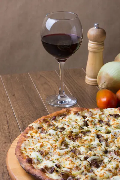 Meat pizza on wooden board. Made with Mozzarella, picanha meat, onion, cheese, tomato sauce. Filet Steak, meat, pepper grinder, glass of red wine. Vertical photo of pizza dough.
