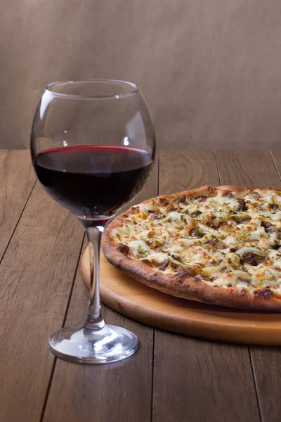 Delicious meat pizza on wooden board. Made with Mozzarella, picanha meat, onion, cheese, tomato sauce. Filet Steak, meat. Glass of wine for tasting.