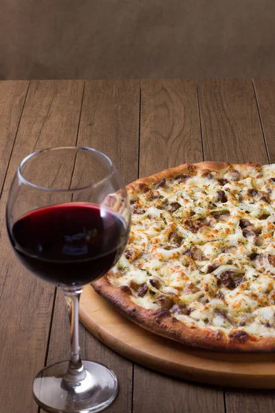 Delicious meat pizza on wooden board. Made with Mozzarella, picanha meat, onion, cheese, tomato sauce. Filet Steak, meat. Glass of wine. To enjoy.