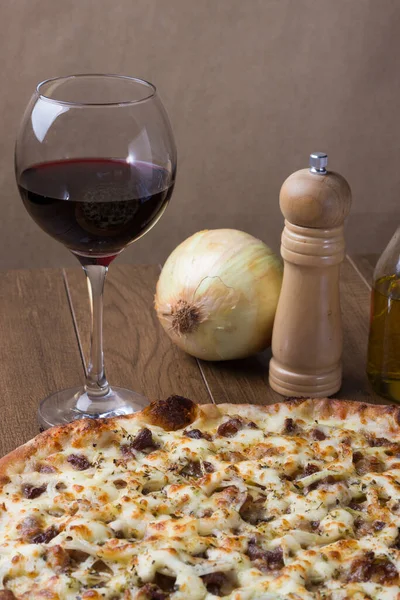 Meat pizza on wooden board. Made with Mozzarella, picanha meat, onion, cheese, tomato sauce. Filet Steak, meat, pepper grinder, glass of red wine, fork and knife. Vertical photo.