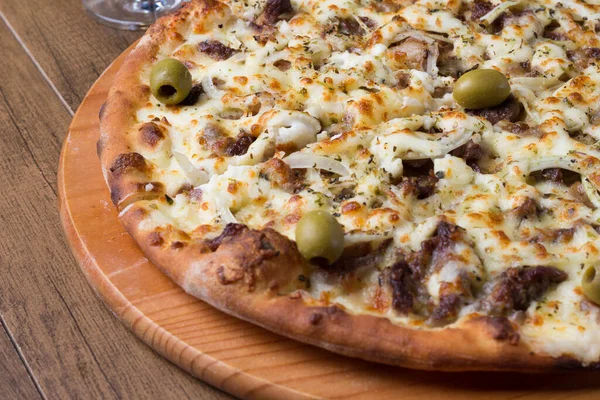 Meat pizza on wooden board. Made with Mozzarella, picanha meat, onion, cheese, tomato sauce and olives. Filet Steak, meat.