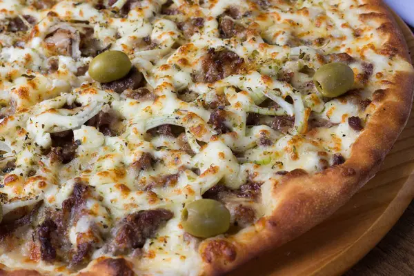 Meat pizza on wooden board. Made with Mozzarella, picanha meat, onion, cheese, tomato sauce and olives. Filet Steak, meat. Mouth-watering food.