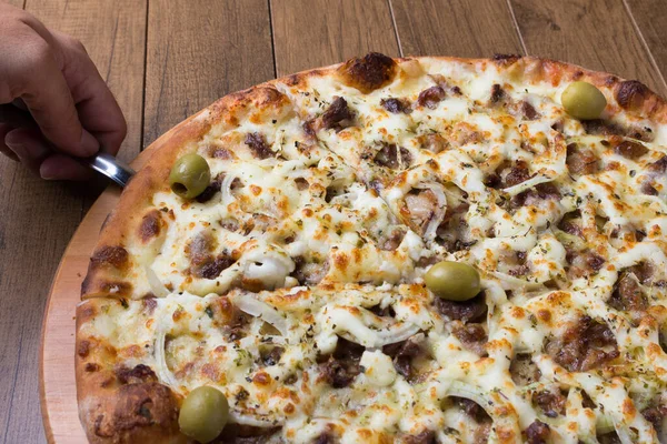 Meat pizza on wooden board. Made with Mozzarella, picanha meat, onion, cheese, tomato sauce and olives. Filet Steak, meat. A slice is served.