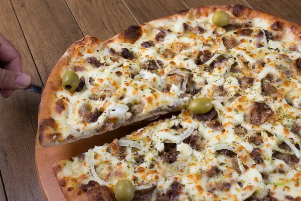 Meat pizza on wooden board. Made with Mozzarella, picanha meat, onion, cheese, tomato sauce and olives. Filet Steak, meat. Serving slice of pizza.