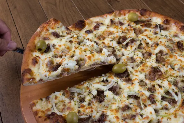 Meat pizza on wooden board. Made with Mozzarella, picanha meat, onion, cheese, tomato sauce and olives. Filet Steak, meat. Serving delicious slice.