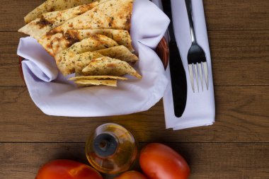 Costini. Baharatlı hamur. Çatal ve bıçak beyaz bir peçetede. Restoranlarda ve pizzacılarda aperatif olarak yiyecek veriliyor. Kırmızı domatesler, zeytinyağı. Tipik İtalyan yemekleri. Üstten yatay olarak fotoğraf.