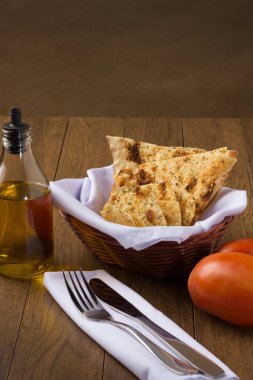 Costini. Baharatlı hamur. Çatal ve bıçak beyaz bir peçetede. Restoranlarda ve pizzacılarda aperatif olarak yiyecek veriliyor. Kırmızı domatesler, zeytinyağı. Tipik İtalyan yemekleri. Dikey fotoğrafçılık.