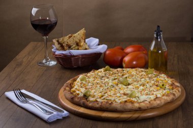 Akılda kalıcı tavuk aromalı pizza. Mozarella, tavuk, krem peynir, yeşil zeytin, mısır ve kırmızı domates sosuyla yapılmış. Kırmızı şarap, porsiyon crostini, zeytinyağı ile servis edilir. peçete..