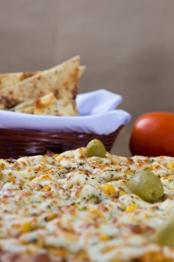 Ahşap bir tahtanın üzerinde servis edilen Catupiry Chicken aromalı pizza. Mozarella, tavuk, krem peynir, yeşil zeytin ve kırmızı domates sosuyla yapılmış..