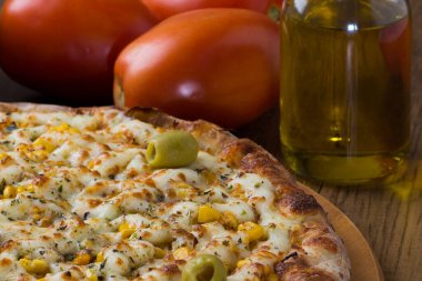 Ahşap bir tahtanın üzerinde servis edilen Catupiry Chicken aromalı pizza. Mozarella, tavuk, krem peynir, yeşil zeytin, mısır ve kırmızı domates sosuyla yapılır..