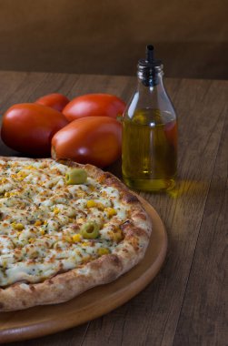 Ahşap bir tahtanın üzerinde servis edilen Catupiry Chicken aromalı pizza. Mozarella, tavuk, krem peynir, yeşil zeytin, mısır ve kırmızı domates sosuyla yapılır..