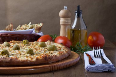 Gratin Loin Pizza. Mozzarella, Kanada usulü sığır filetosu, kremalı süt ve yeşil zeytin. Yanında crostini, kırmızı domates, zeytinyağı, karabiber öğütücü, çatal ve bıçak beyaz peçete ve maydanozla servis edilir. Kapat