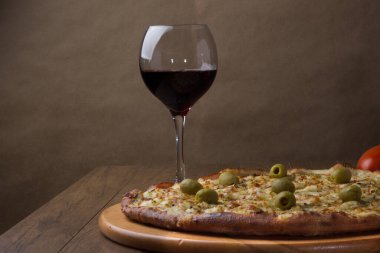 Tahta tahtada servis edilen Gratin Sirloin Pizza. Mozzarella, Kanada usulü sığır filetosu, kremalı süt ve yeşil zeytin. Bir kadeh kırmızı şarap. Tipik İtalyan yemekleri. Yatay fotoğrafçılık.