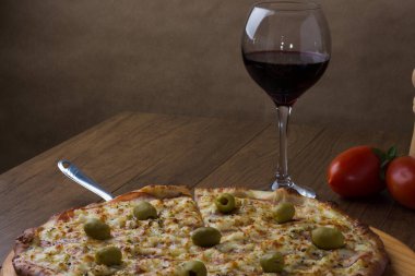 Tahta tahtada servis edilen lezzetli Gratin sığır filetosu pizzası. Mozzarella, Kanada usulü sığır filetosu, kremalı süt ve yeşil zeytin. Bir bardak kırmızı şarap, domates ve baharat.