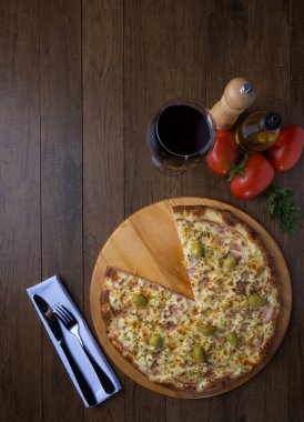 Tahta tahtada servis edilen Gratin Sirloin Pizza. Mozzarella, Kanada usulü sığır filetosu, kremalı süt ve yeşil zeytin. Dilimlenmiş. Şarap Kadehi.