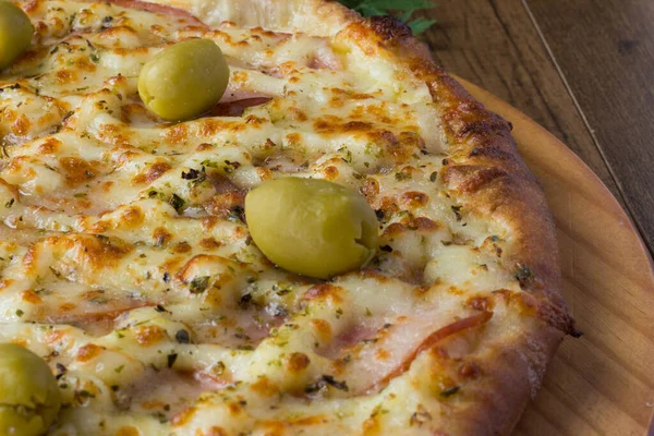 Tahta tahtada servis edilen lezzetli Gratin sığır filetosu pizzası. Mozzarella, Kanada usulü sığır filetosu, kremalı süt ve yeşil zeytin. Tipik İtalyan yemekleri. Yatay olarak makro fotoğrafçılık.