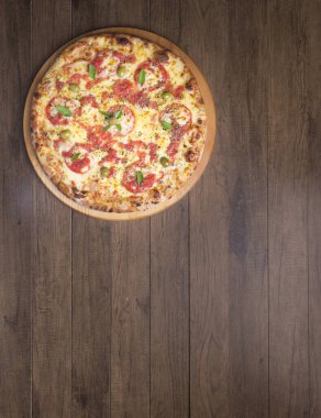 Lezzetli pizza hamuru, Mozzarella, domates, marjoram ve yeşil zeytinle yapılmış pizza. Tahta bir tahtanın üzerinde servis edilmiş. Napoli Pizzası. Yenilenmiş gastronomi. Üst sol dikey üstün gurme fotoğrafı.