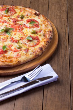 Lezzetli pizza hamuru, Mozzarella, domates, marjoram ve yeşil zeytinle yapılmış pizza. Tahta bir tahtanın üzerinde servis edilmiş. Napoli Pizzası. Gurme gastronomi. Çatal ve bıçak. Tipik İtalyan yemekleri..