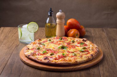 Lezzetli pizza hamuru, Mozzarella, domates, marjoram ve yeşil zeytinle yapılmış pizza. Tahtanın üzerinde. Napoli Pizzası. Limonlu soda ve buz küpleri. Vazgeçilemez gastronomik