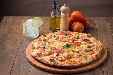 Lezzetli pizza hamuru, Mozzarella, domates, marjoram ve yeşil zeytinle yapılmış pizza. Tahtanın üzerinde. Napoli Pizzası. Limonlu soda ve buz küpleri. Merkezileştirilmiş. Gastronomi.