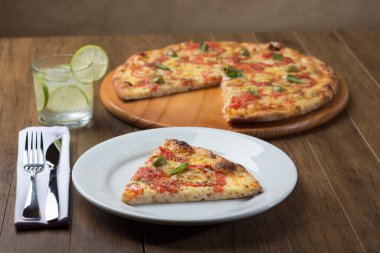 Mozzarella peyniri, domates, fesleğen yaprağı, yeşil zeytin ve bolca sevgi ve özenle tatlandırılmış sıcak pizza dilimi. Napoli Pizzası. Odaklanmamış arkaplan ögeleri.