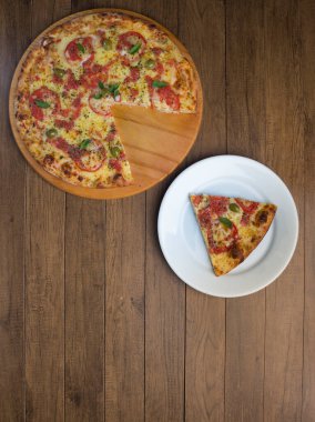 Mozzarella peynirli, domatesli, fesleğenli ve yeşil zeytinli dilimlenmiş pizza. Beyaz tabakta servis ediliyor. Dünyadaki çoğu pizzacıda geleneksel yiyecekler var. Dikey Üst Fotoğraf.