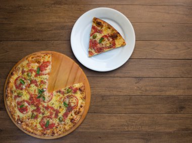 Mozzarella peynirli, domatesli, fesleğenli ve yeşil zeytinli pizza dilimli fotoğraf beyaz bir tabakta servis edilir. Dünyadaki çoğu pizzacıda geleneksel yiyecekler var. Üst Fotoğraf.