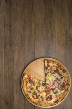 Mozzarella peynirli, domatesli, fesleğenli ve yeşil zeytinli pizza fotoğrafı ahşap bir tahtada servis ediliyor. Yazmak için üst boşluğa sahip elementlerin alt hizalaması.