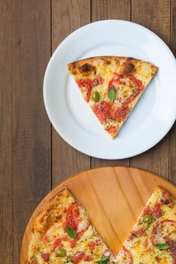 Mozzarella peyniri, domates, fesleğen yaprağı ve yeşil zeytinlerle yapılmış pizza Marguerita 'nın fotoğrafı ahşap bir tahtada servis ediliyor. Tabakta servis edilen pizza dilimi. Makro Fotoğraf Üst Görünümü.