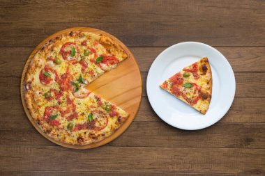 Mozzarella peyniri, domates, fesleğen yaprağı ve yeşil zeytinlerle yapılan pizza Marguerita 'nın en iyi fotoğrafı ahşap bir tahtada servis ediliyor. Tabakta servis edilen pizza dilimi. Pizza servisi..